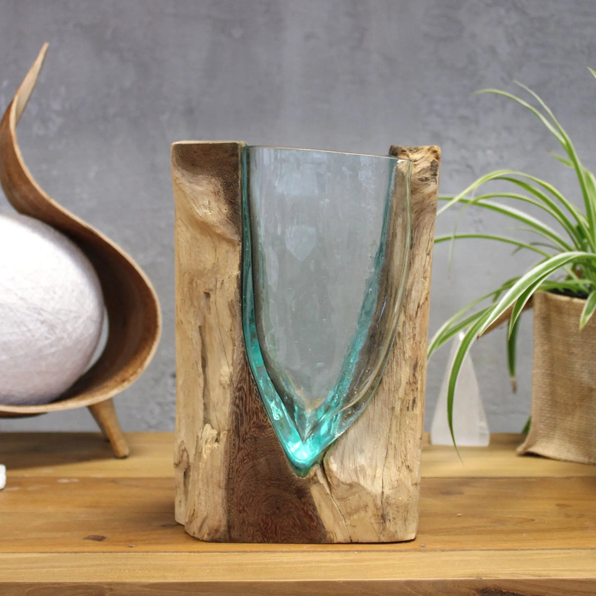 Jarrón de vidrio fundido en forma de V encajado en una base de madera natural, estilo artesanal.