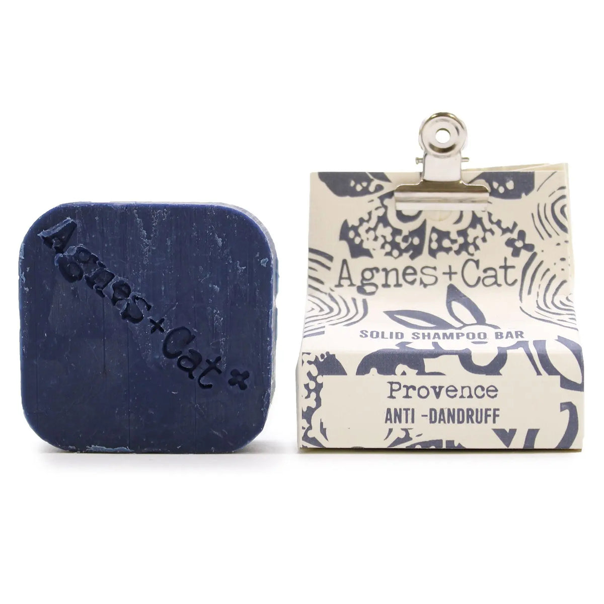 Champú sólido azul "Provence" de Agnes+Cat junto a su envoltorio de papel estampado con una pinza metálica.