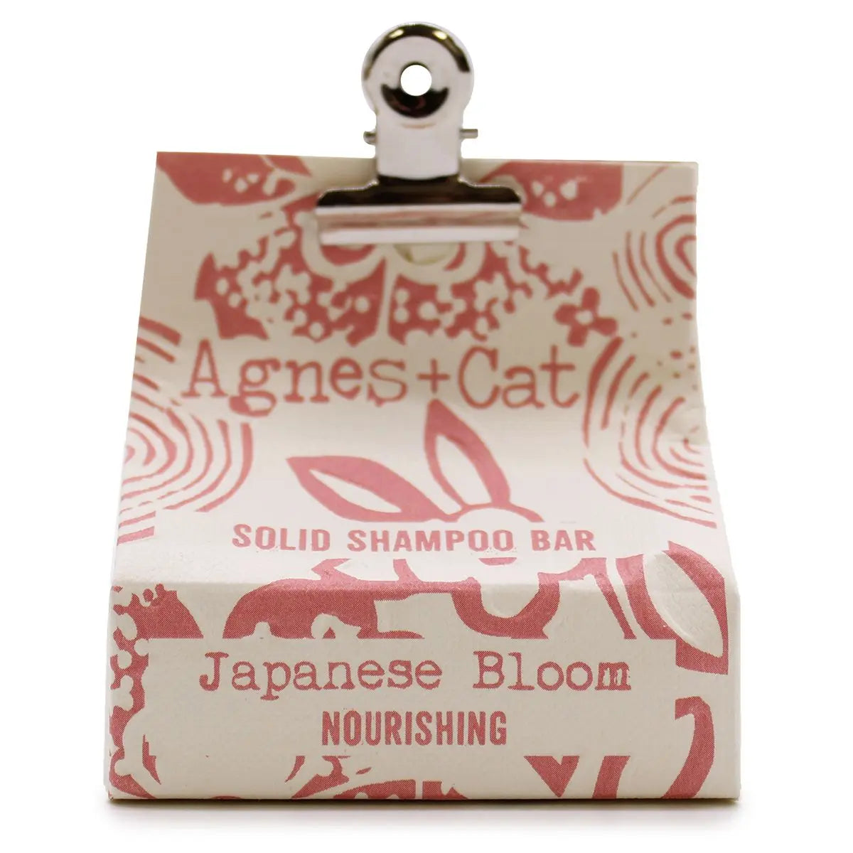 Champú sólido Agnes+Cat Japanese Bloom: pastilla envuelta en papel crema con estampado floral rosa y pinza metálica.