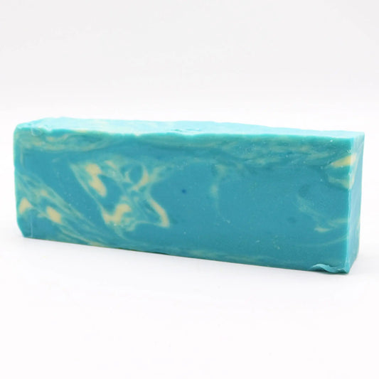 Barra larga de jabón artesanal azul turquesa con vetas crema, textura lisa y forma rectangular sobre fondo blanco.