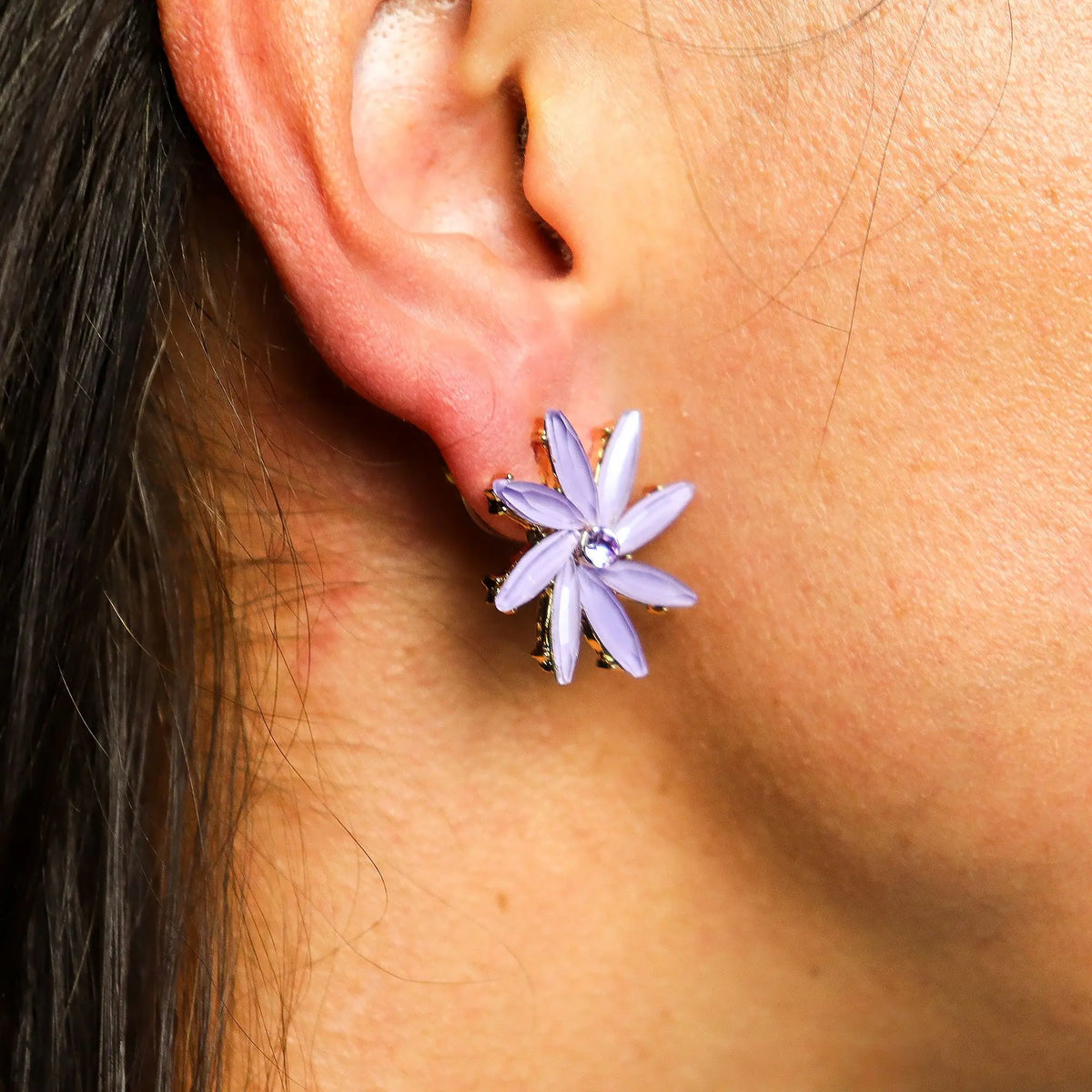 Pendiente en forma de flor color lavanda con centro de cristal brillante colocado en la oreja con estilo vintage