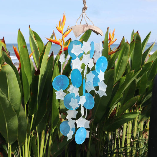Carillón de coco con figuras de concha capiz en forma de estrellas blancas y círculos azules, estilo artesanal.