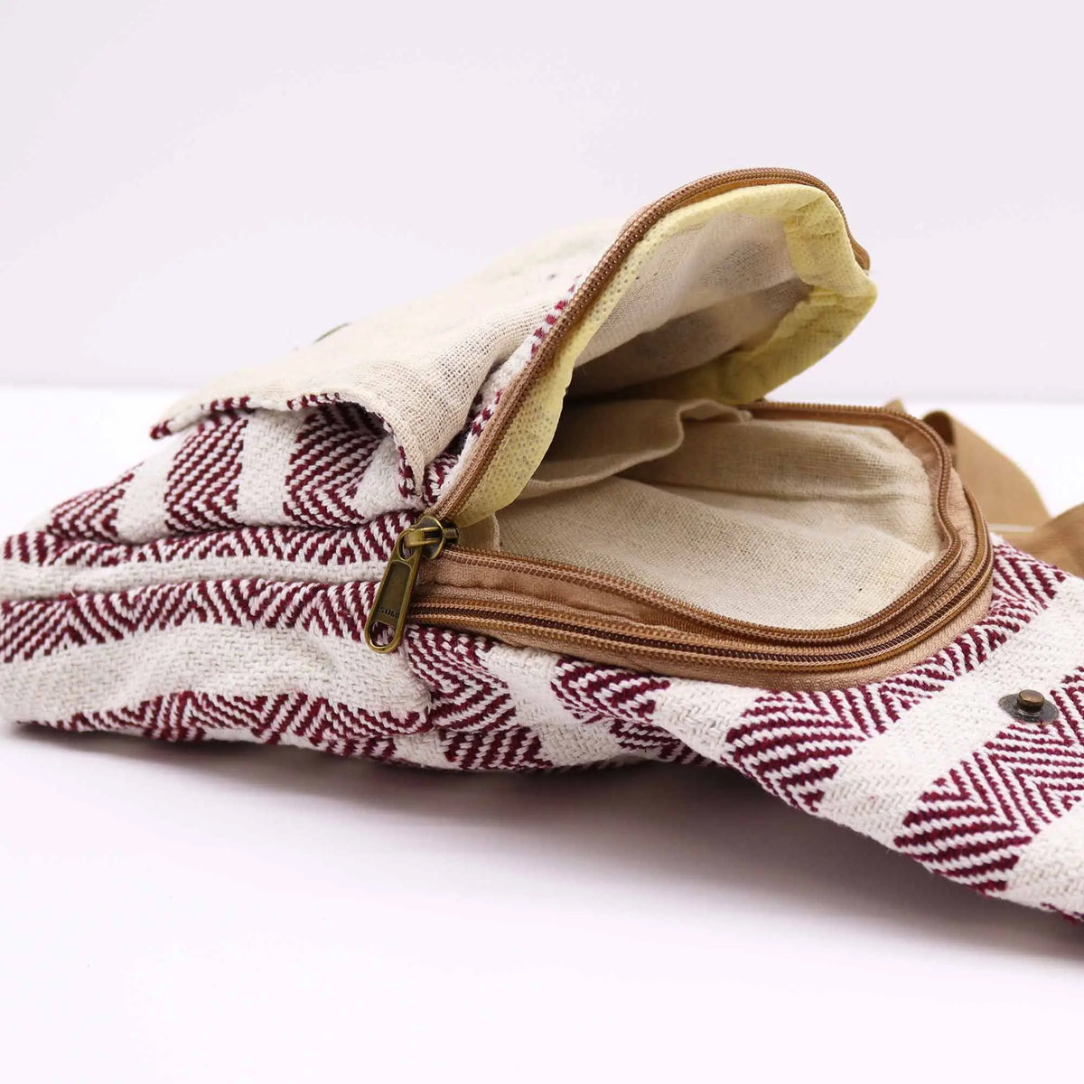 Bolso bandolera de algodón con patrón geométrico en burdeos y blanco, cierre de cremallera y solapa con botón.