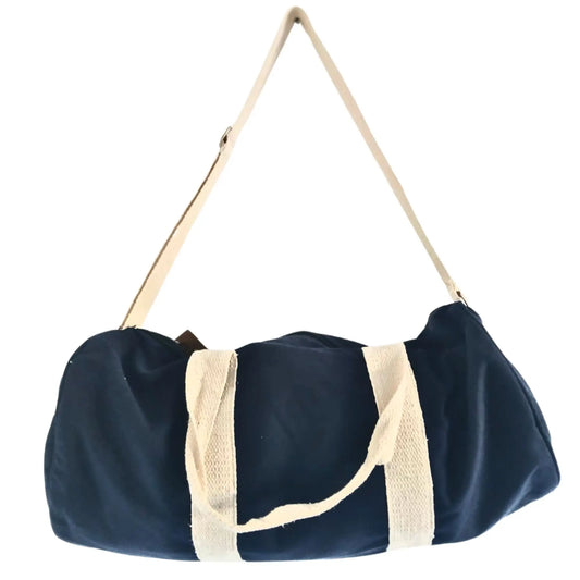 Bolsa de deporte azul marino, forma cilíndrica, de lona con correas y asas de tela color crema. Fondo blanco.