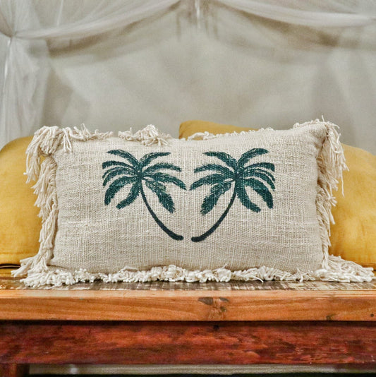 Funda rectangular de lino beige con estampado de dos palmeras verdes y flecos en los bordes. Estilo rústico y tropical.