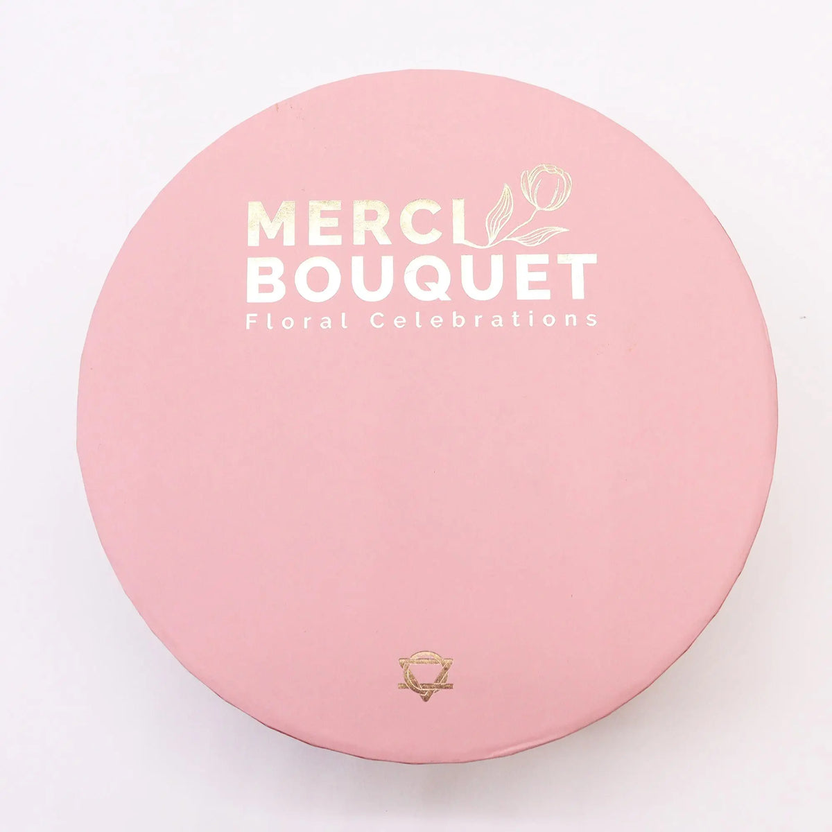 Caja redonda de regalo en color rosa pastel con tipografía y detalles decorativos en tono dorado sobre fondo blanco.