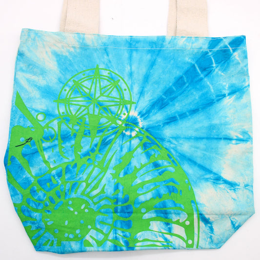 Bolsa de algodón tie-dye azul con estampado verde de concha marina y brújula. Asas de tela natural.