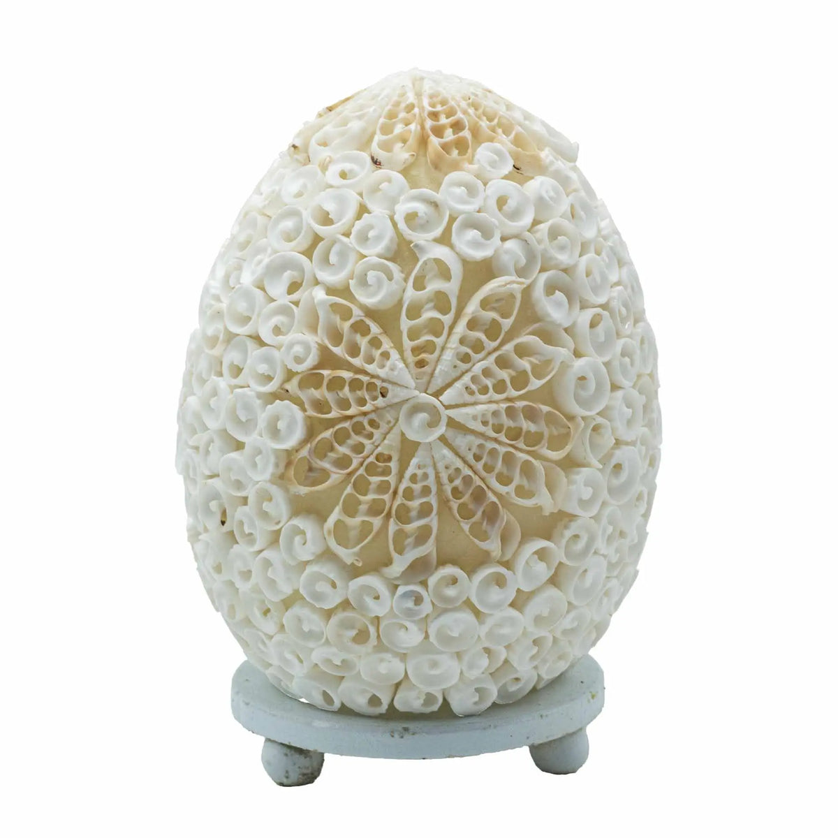 Lámpara ovalada de estilo boho cubierta de conchas marinas blancas naturales en patrón floral, sobre una base pequeña.
