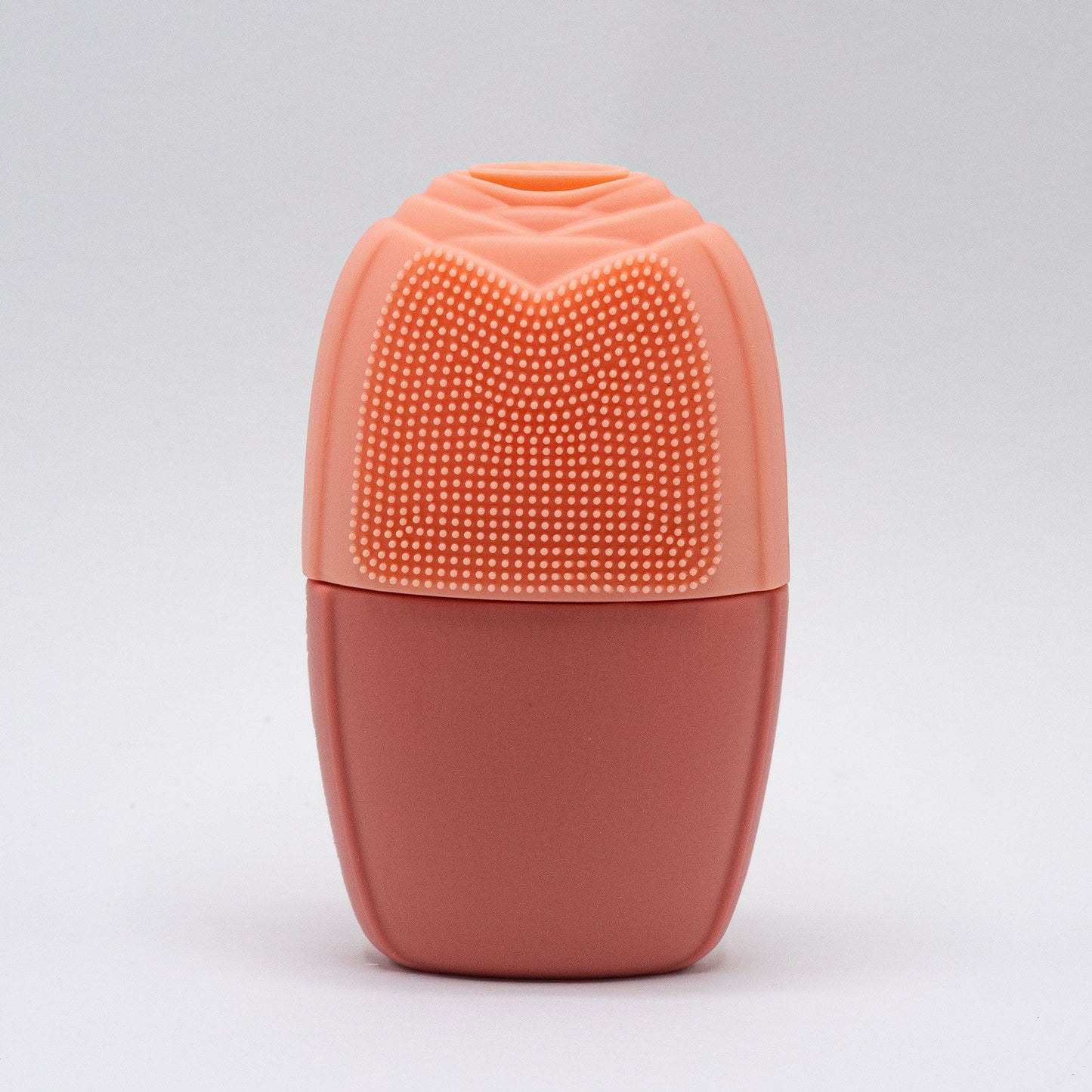 Rodillo facial de silicona color melocotón, con superficie texturizada y forma ergonómica sobre fondo blanco.