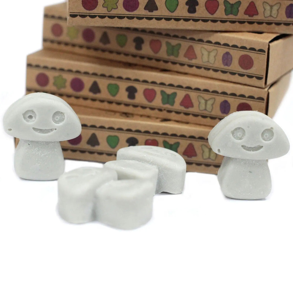 Cajas de cartón kraft con figuras de cera de soja gris con forma de setas sonrientes dispuestas sobre fondo blanco