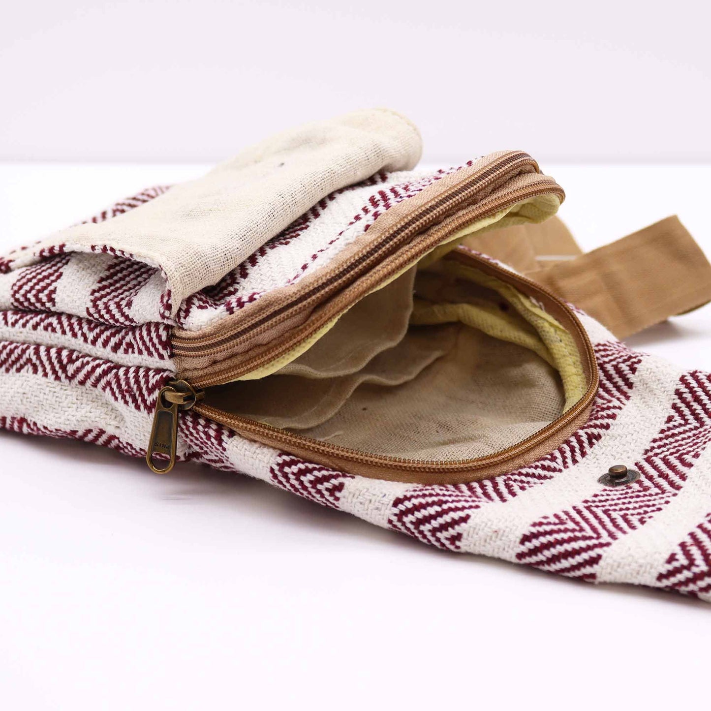Bolso bandolera de algodón con estampado geométrico burdeos y blanco, con cremallera abierta y compartimentos internos.