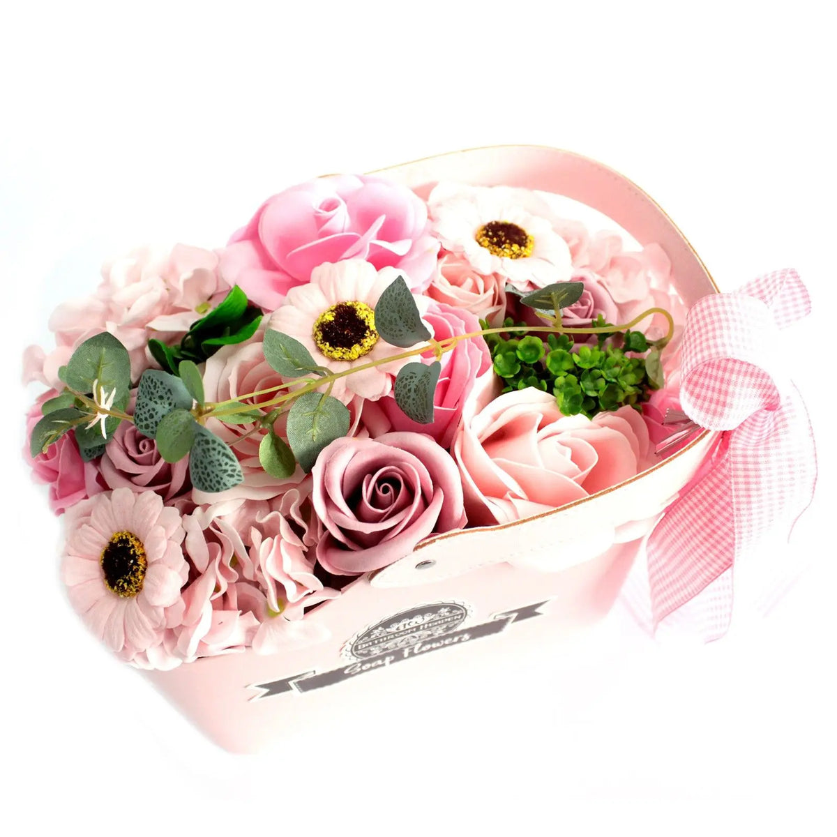 Cesta rosa decorativa con ramo de flores de jabón en tonos rosados, hojas verdes y un lazo a cuadros en el asa.