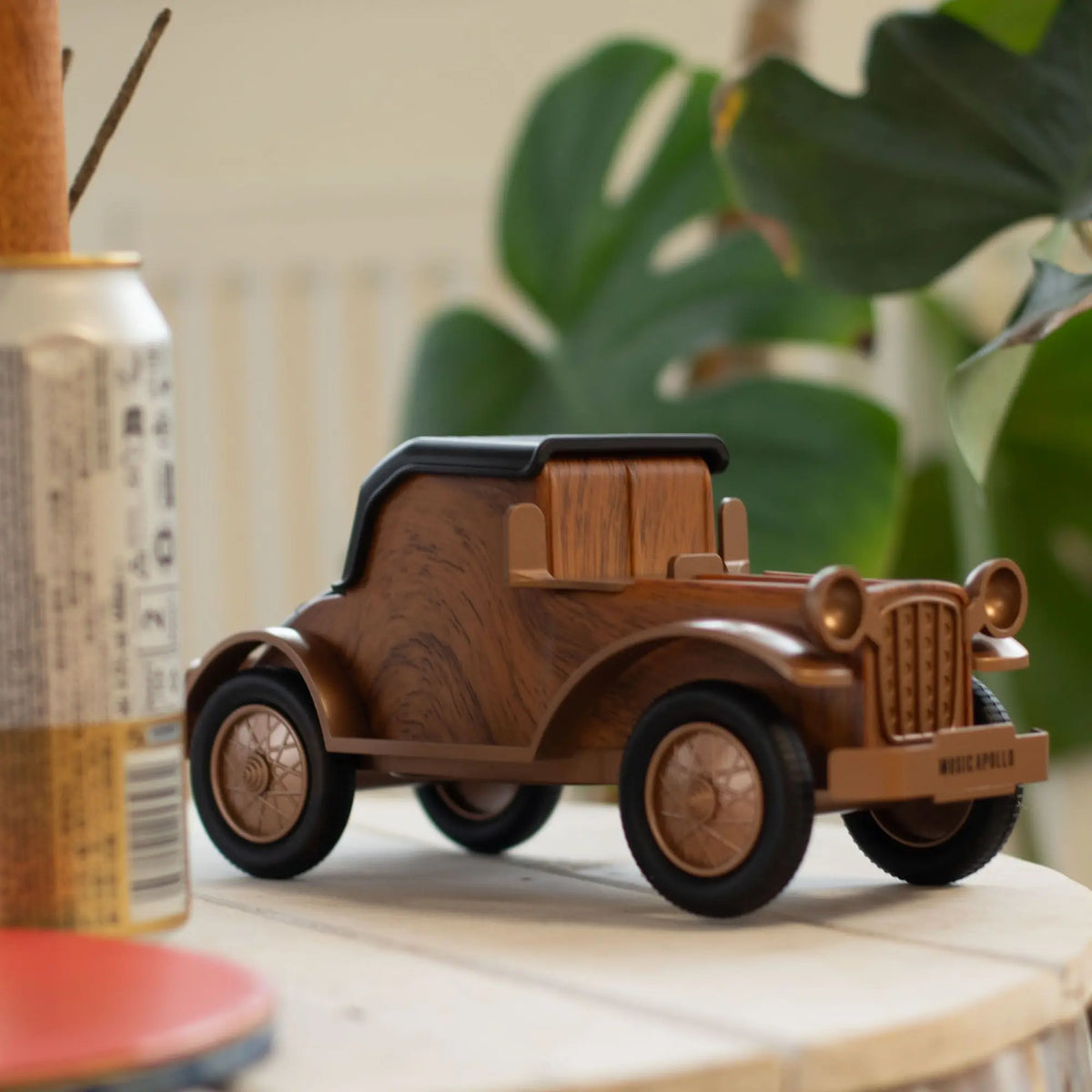 Altavoz Bluetooth vintage con forma de coche clásico en madera marrón y plástico negro; sirve también como soporte móvil.
