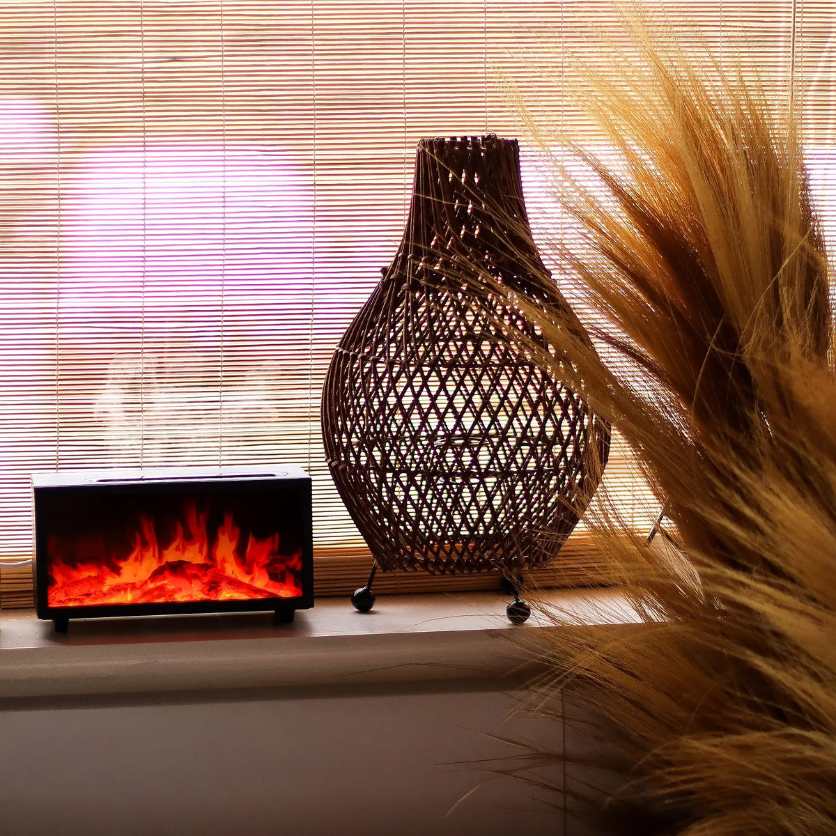 Difusor de aroma negro rectangular con efecto de llama LED realista y vapor, junto a una lámpara de mimbre decorativa.