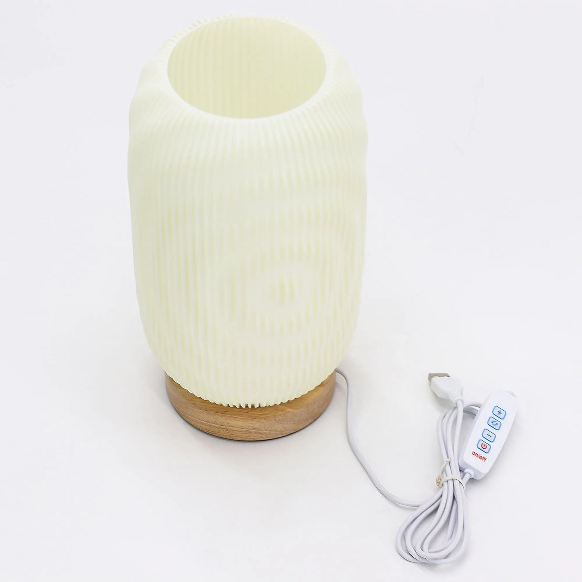 Lámpara cilíndrica de textura estriada color crema sobre base de madera, con cable USB y control de tres ajustes.