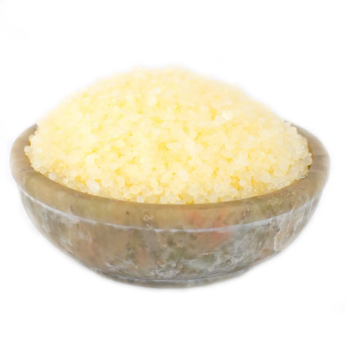 Cuenco de piedra natural con granos aromáticos de color amarillo brillante sobre fondo blanco.