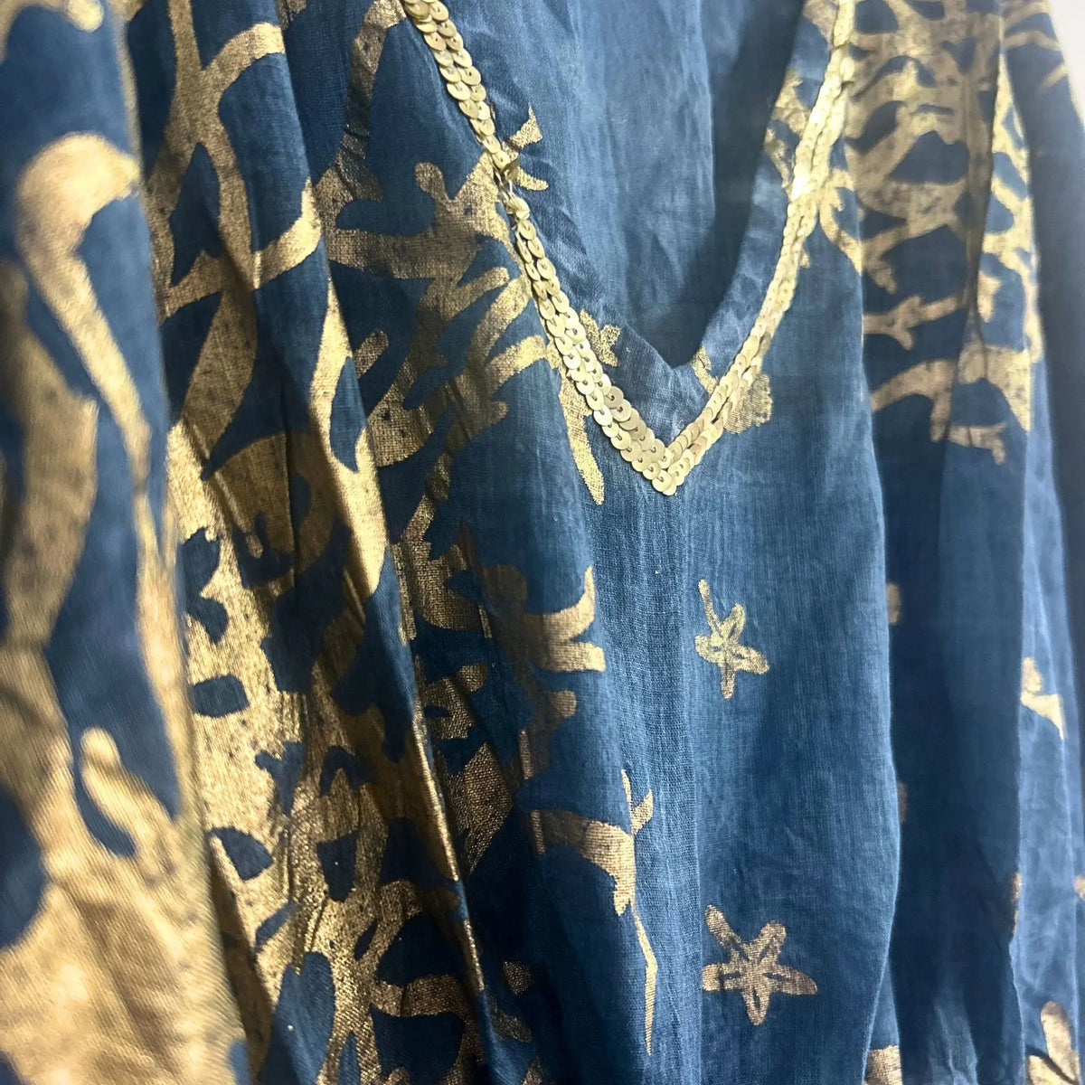 Kaftán azul marino con estampado de coral dorado y cuello en pico decorado con lentejuelas doradas.