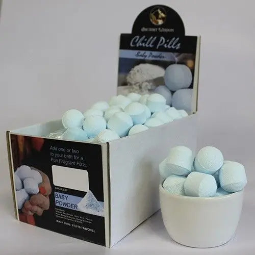 Caja con mini bombas de baño esféricas, color azul claro, textura porosa, junto a un cuenco lleno de las mismas.