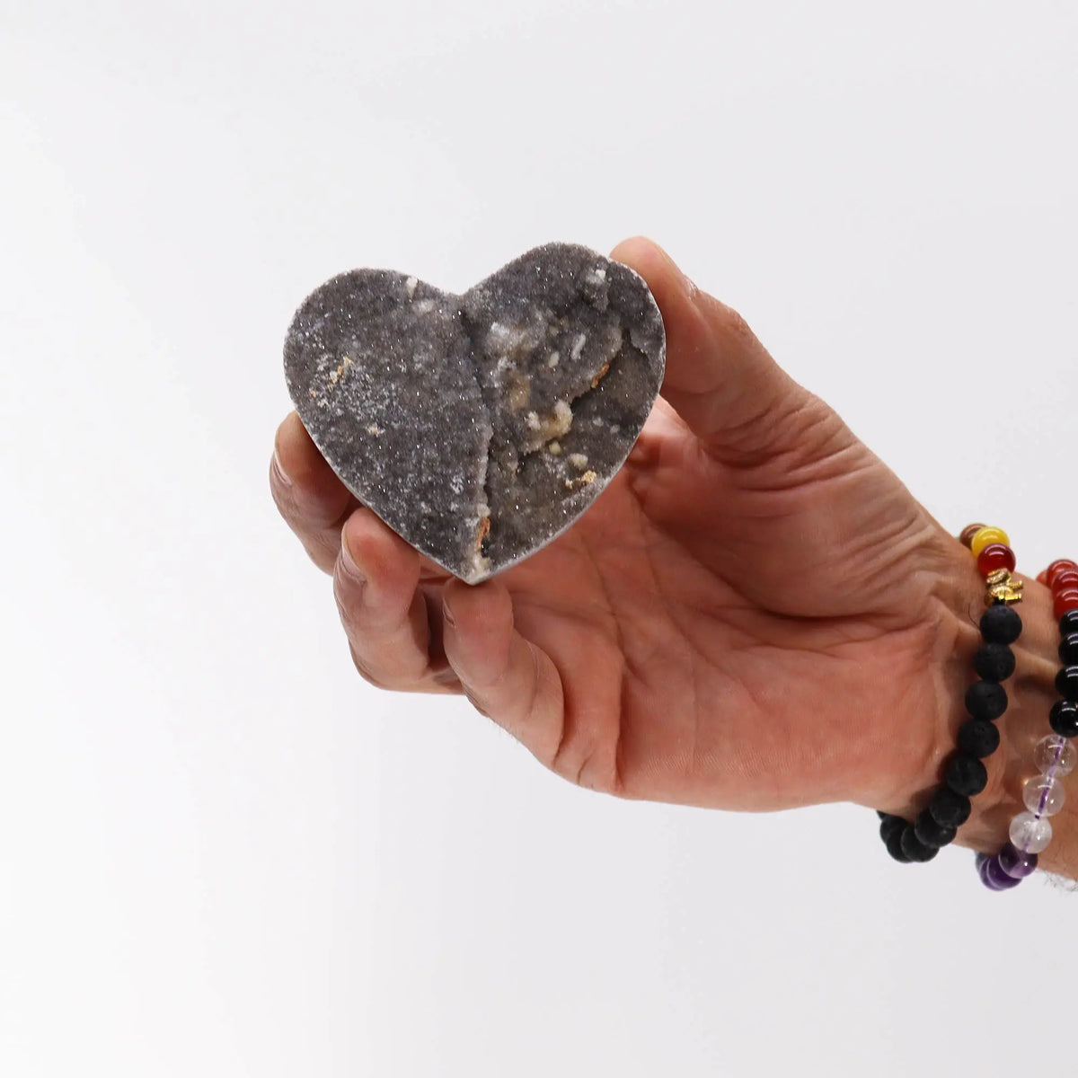 Jabón artesanal en forma de corazón, color gris oscuro con texturas naturales y detalles en blanco.