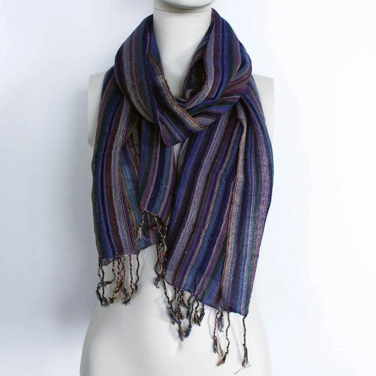 Bufanda bohemia a rayas azules y moradas con hilos dorados brillantes y flecos en los extremos sobre maniquí blanco.