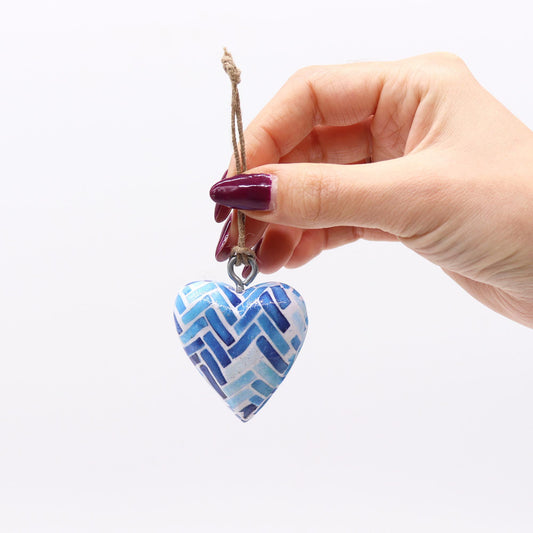 Corazón decorativo de cerámica en tonos azules con diseño de zigzag, colgado con cuerda natural.