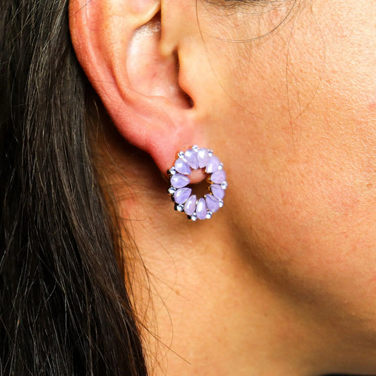 Pendiente de aro con cristales en forma de lágrima color lavanda, dispuesto en círculo sobre el lóbulo de una oreja.