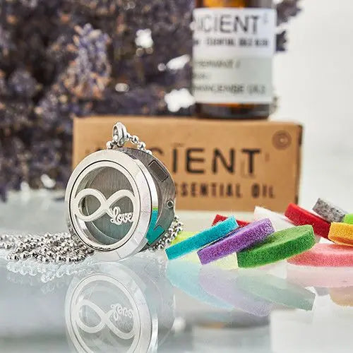 Collar plateado con corazón infinito y cadena, acompañando aceite esencial y coloridas esencias de fieltro.
