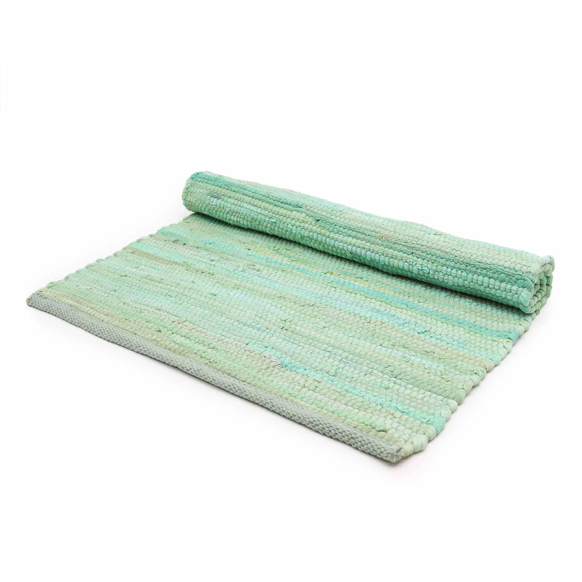 Alfombra rectangular verde tejida a mano en algodón y yute, parcialmente enrollada, sobre fondo blanco.