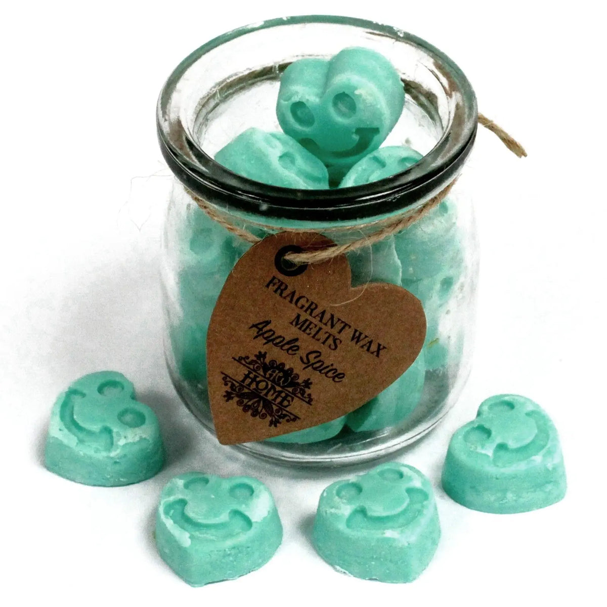 Frasco de vidrio con piezas de cera de soja verde en forma de corazón con cara sonriente y etiqueta de cartón.