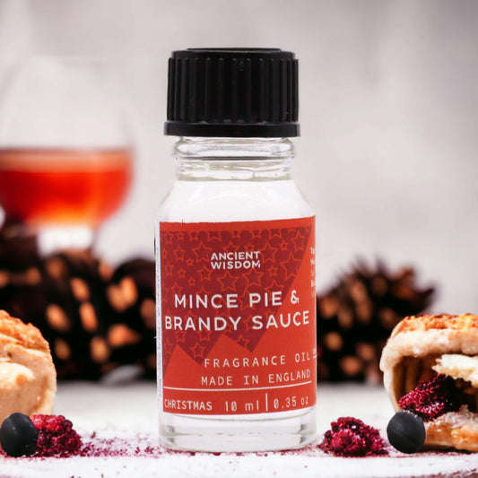 Frasco de vidrio de 10ml con etiqueta roja de aceite aromático "Pastel de frutas y salsa de brandy" sobre fondo festivo.