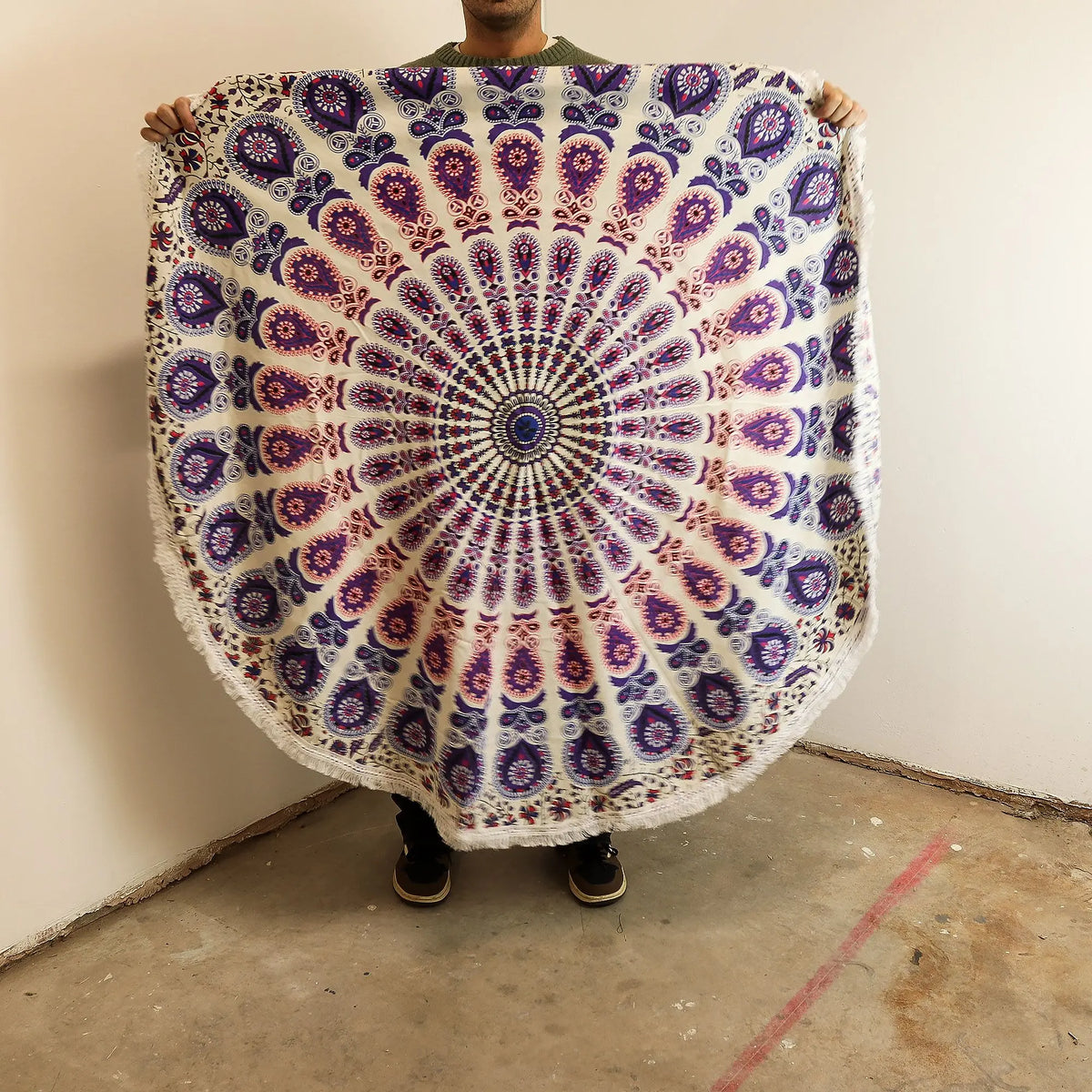 Tapiz circular de algodón con diseño de mandala en tonos púrpura y detalles de pavo real. Mide 130 cm y tiene flecos.