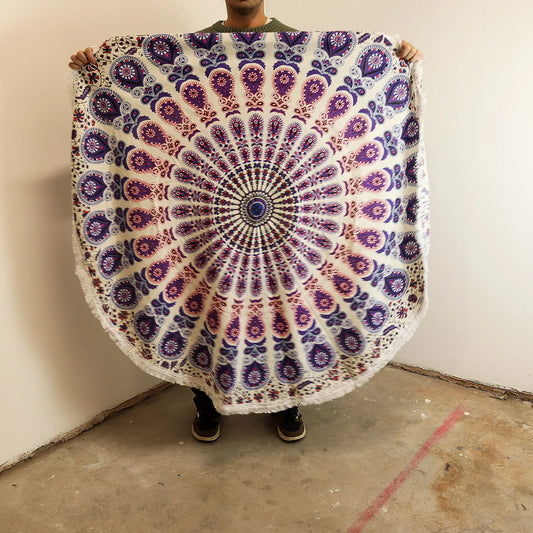 Tapiz circular de algodón con diseño de mandala en tonos púrpura y detalles de pavo real. Mide 130 cm y tiene flecos.