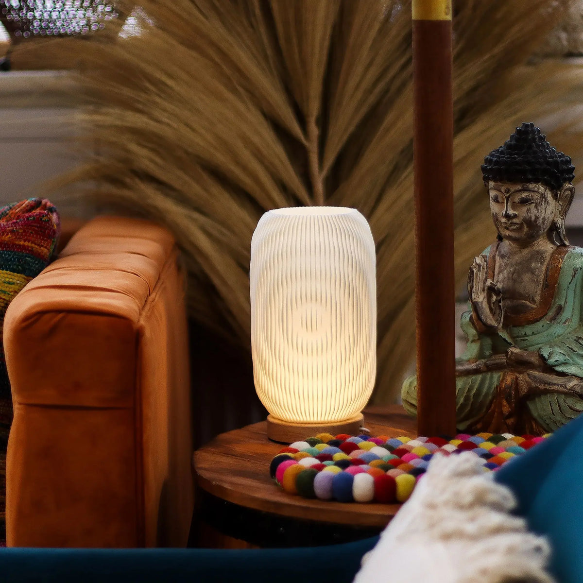 Lámpara de mesa cilíndrica con estrías verticales, luz cálida, base de madera y diseño moderno sobre mesa redonda.