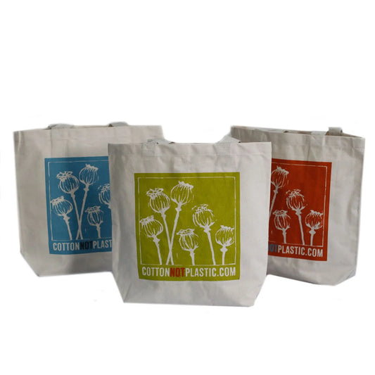 Tres bolsas de algodón crudo con estampado de cabezas de amapola en colores azul, verde y naranja sobre fondo blanco.