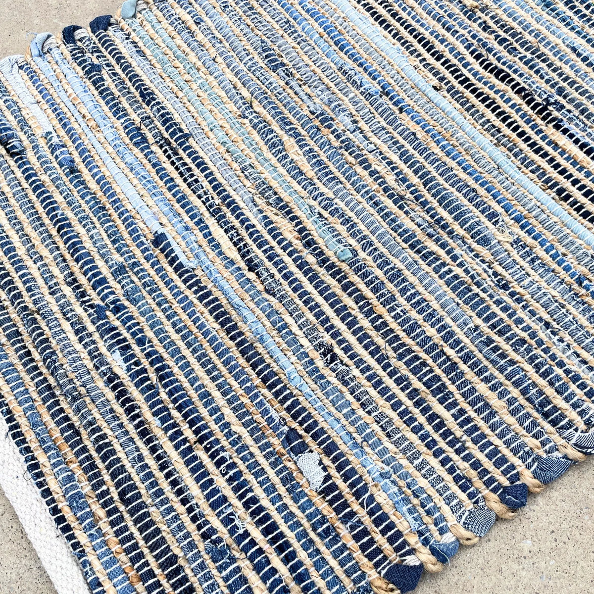 Alfombra rectangular de yute y algodón reciclado en tonos azules y beige, con textura trenzada artesanal.