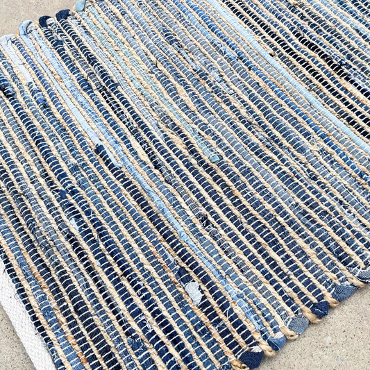 Alfombra rectangular de yute y algodón reciclado en tonos azules y beige, con textura trenzada artesanal.