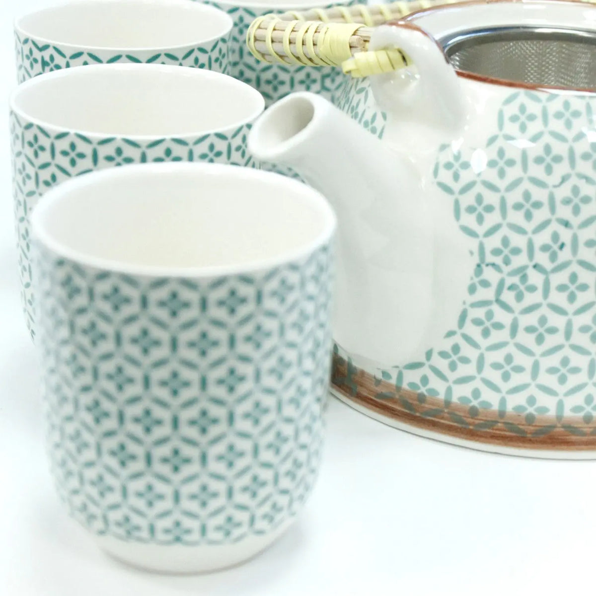 Set de tetera y tazas de cerámica blanca con patrón de mosaico verde y asa de mimbre, incluye colador metálico.