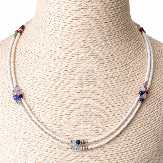 Collar de cuentas blancas y multicolores, estilo bohemio, con detalles en piedras preciosas y cierre metálico.