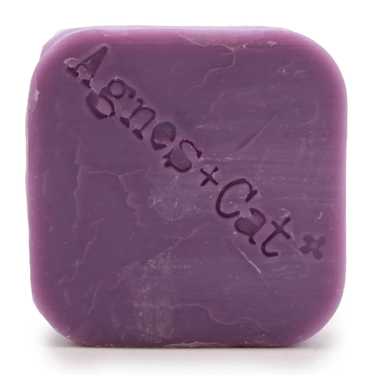 Champú sólido color violeta con textura natural y el logo Agnes + Cat grabado sobre su superficie cuadrada.