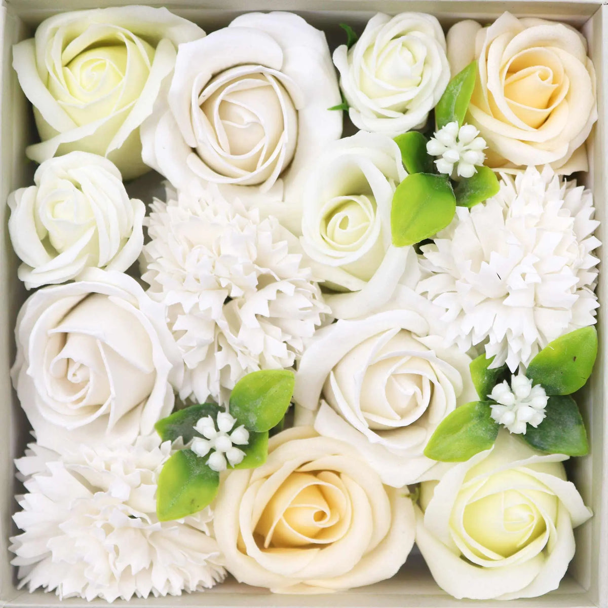 Caja cuadrada con flores de jabón en tonos blanco y marfil, decorada con pequeñas hojas verdes y detalles florales.