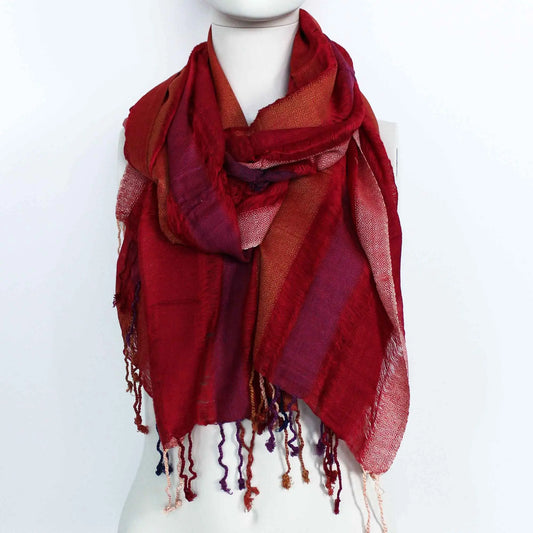 Bufanda bohemia grande en tonos rojos y púrpuras, con patrón geométrico, textura tejida y flecos en los extremos.