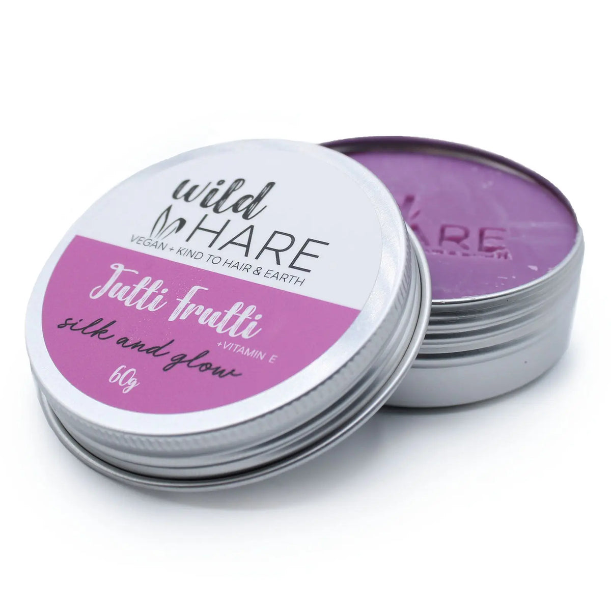 Champú sólido circular de color morado en una lata metálica redonda con etiqueta rosa y blanca sobre fondo blanco.