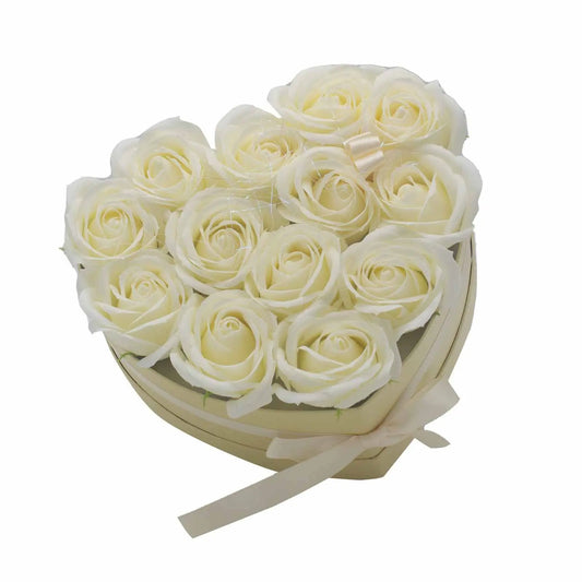 Caja de regalo en forma de corazón con 13 rosas de jabón color crema y un lazo decorativo sobre fondo blanco.