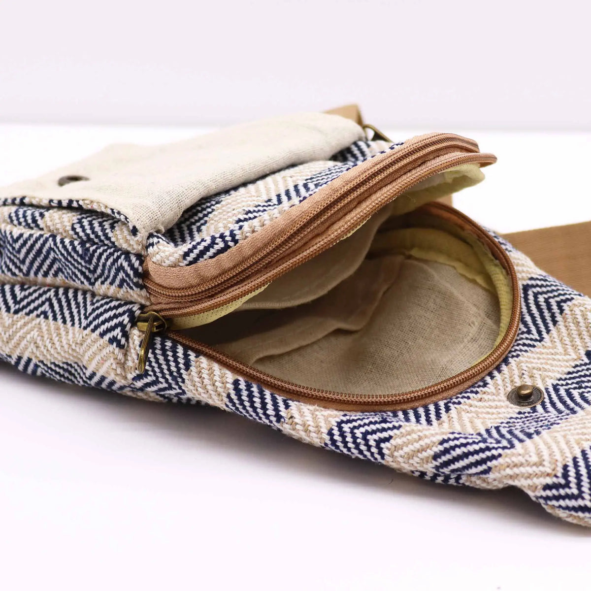 Bandolera de algodón con estampado en zigzag azul marino y beige, cierre de cremallera, bolsillo y correa marrón.