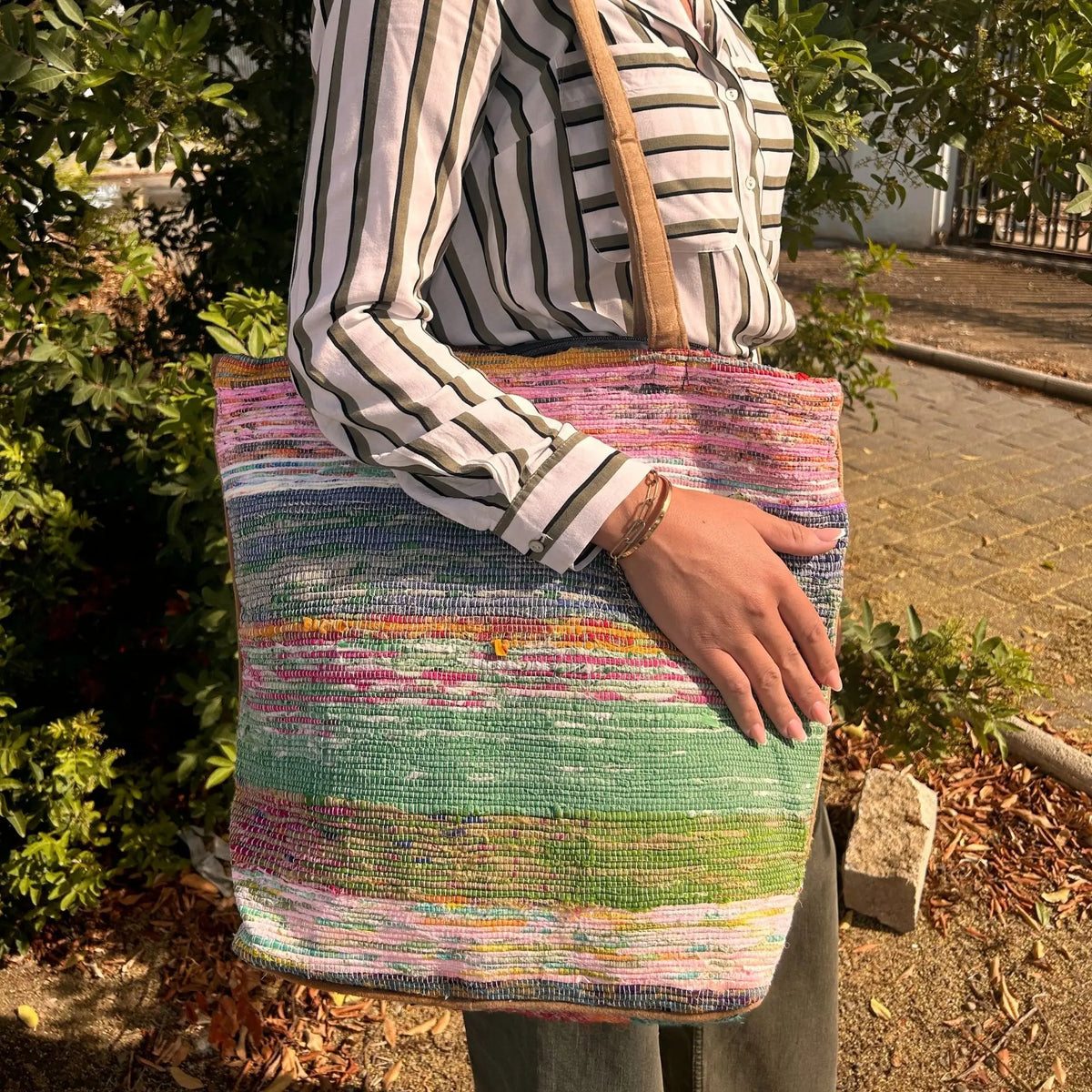Bolso grande hecho de tapetes reciclados con texturas coloridas en tonos rosa y verde, con correas de tela resistente