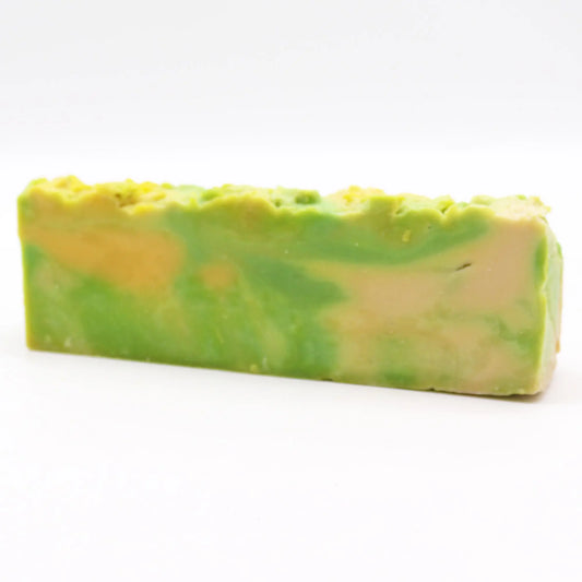 Barra de jabón artesanal de noni rectangular en tonos verde y amarillo con textura irregular en la parte superior sobre fondo blanco.