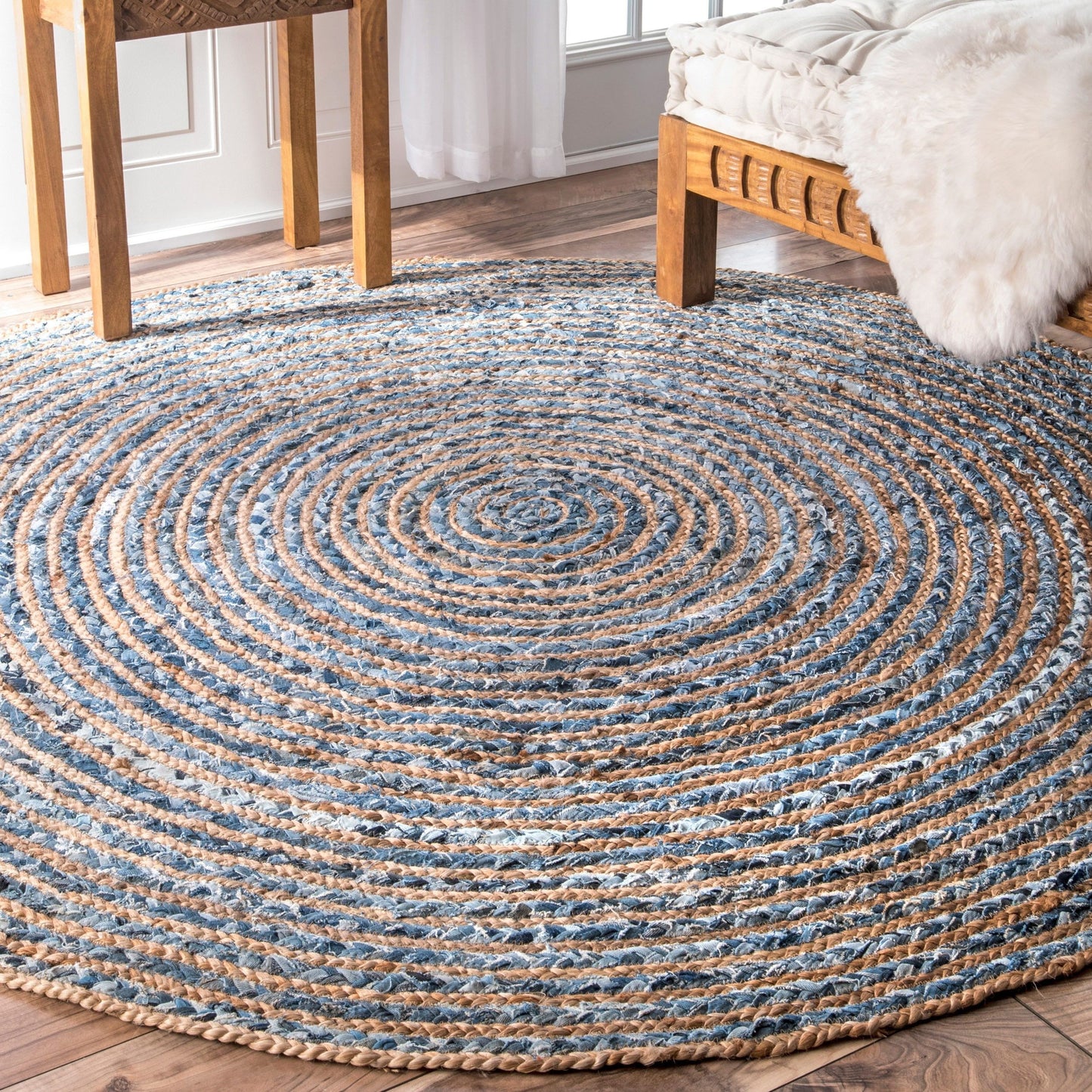 Alfombra redonda tejida en espiral con fibras de yute natural y mezclilla azul reciclada, estilo rústico.