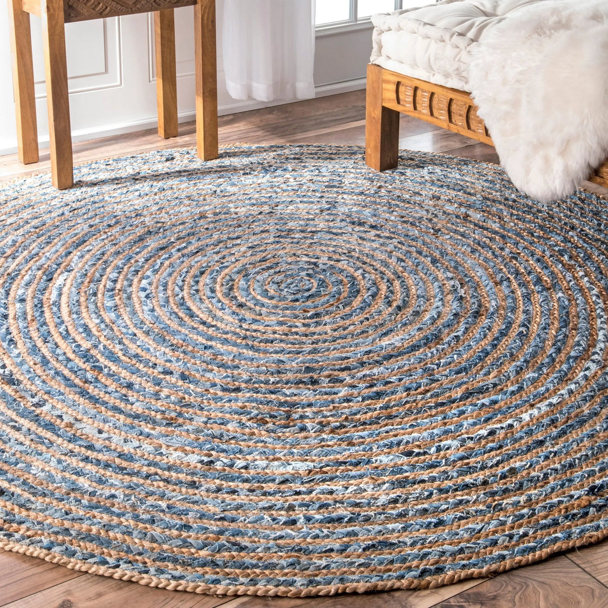 Alfombra redonda tejida en espiral con fibras de yute natural y mezclilla azul reciclada, estilo rústico.