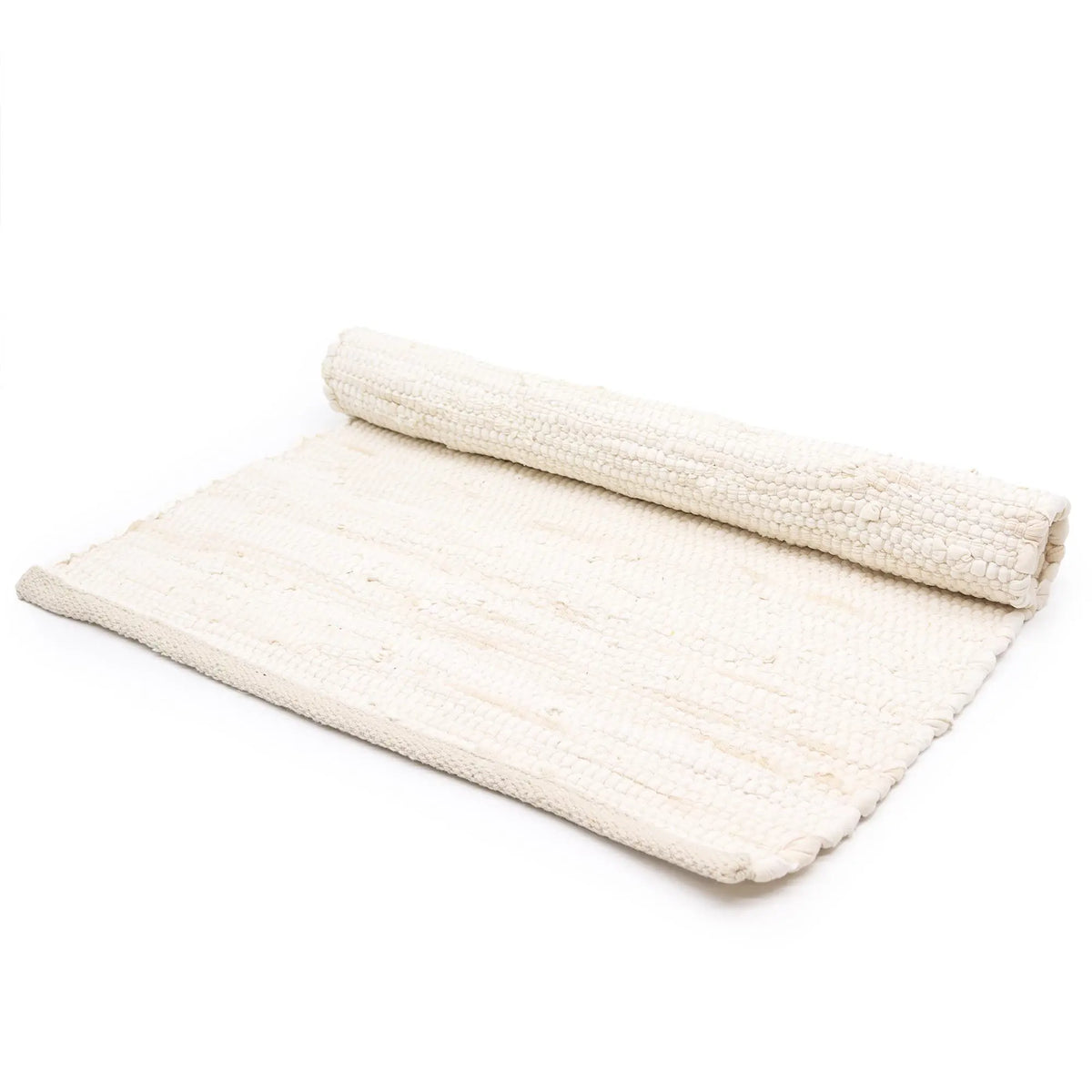 Alfombra rectangular de algodón color crema, tejida a mano con textura artesanal, parcialmente enrollada.