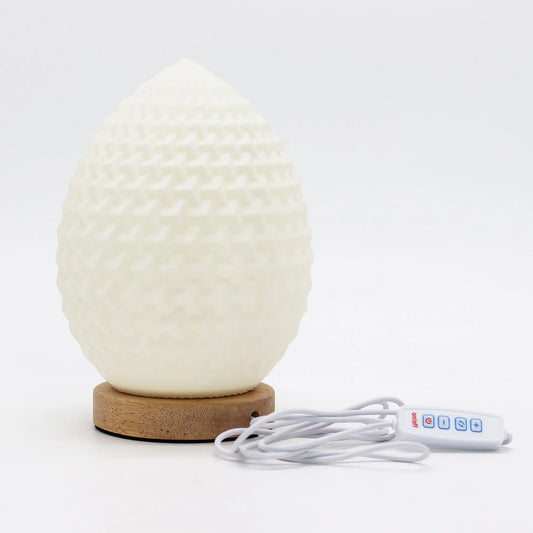 Lámpara blanca en forma de lágrima con textura geométrica, base de madera clara y cable USB con mando de control.